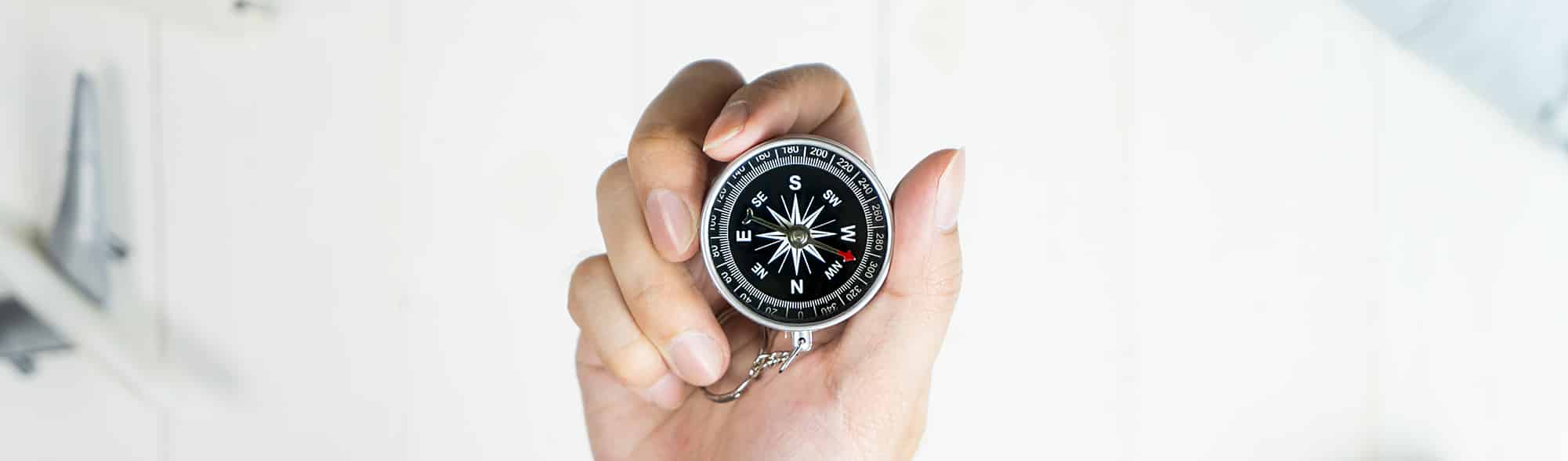 Explorer holding compass surrounded by travel accessories